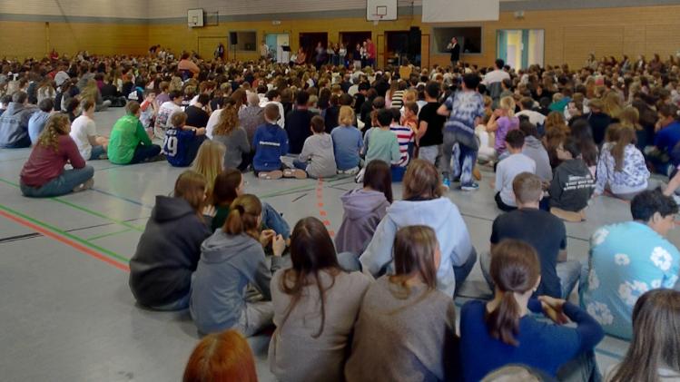 Schülerinnen und Schüler sitzen in der Turnhalle und feiern gemeinsam einen Gottesdienst.