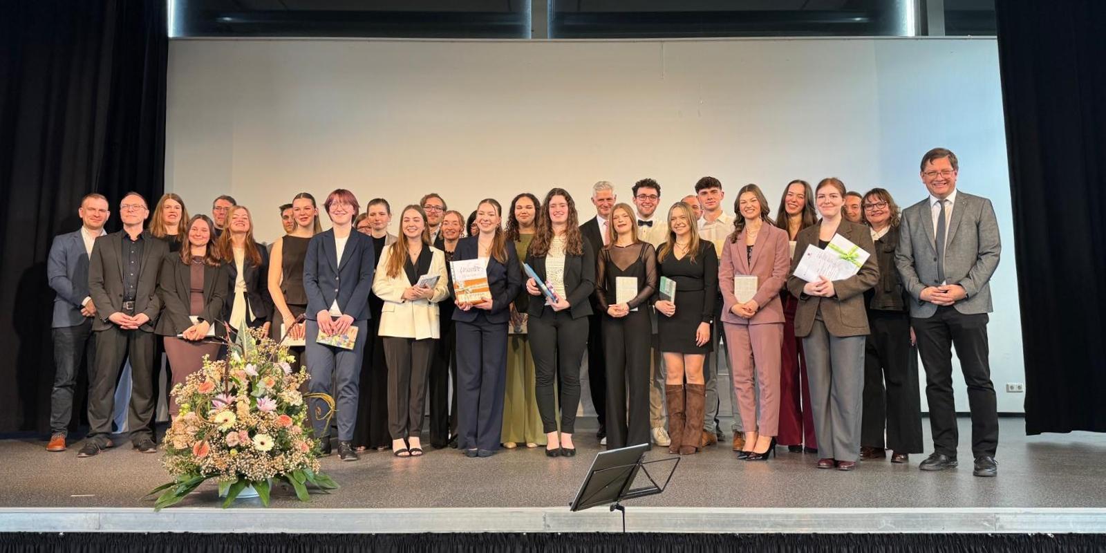 Die Preisträger stehen auf der Bühne der Aula der Schule.