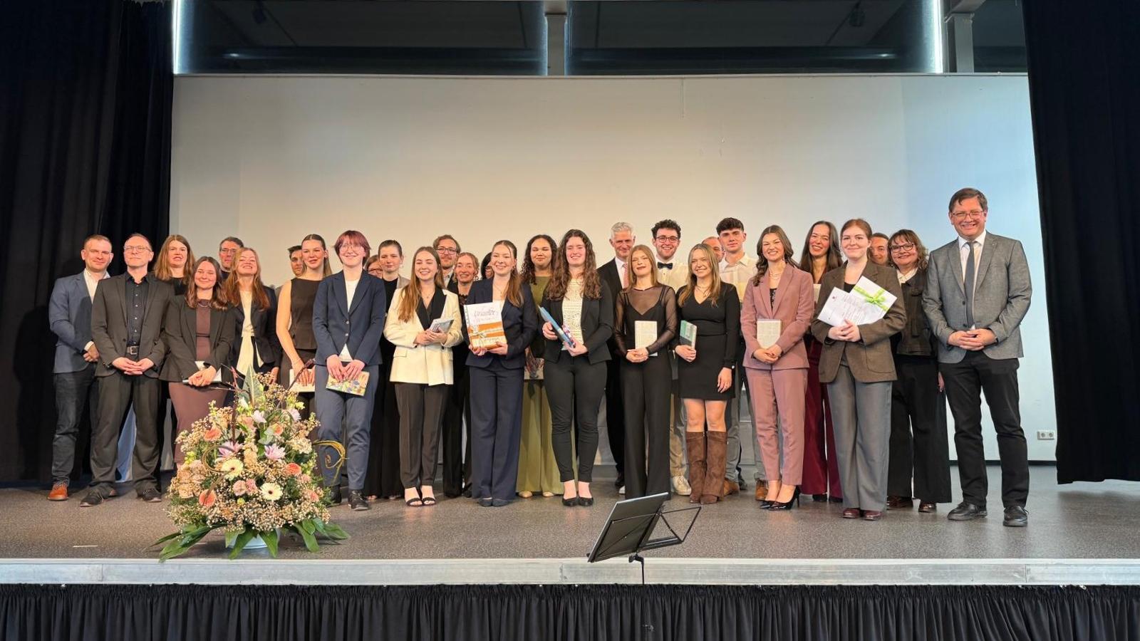 Die Preisträger stehen auf der Bühne der Aula der Schule.
