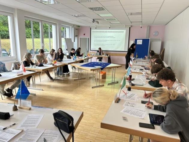 Die Gruppe sitzt und Tischen und bearbeitet Unterlagen.