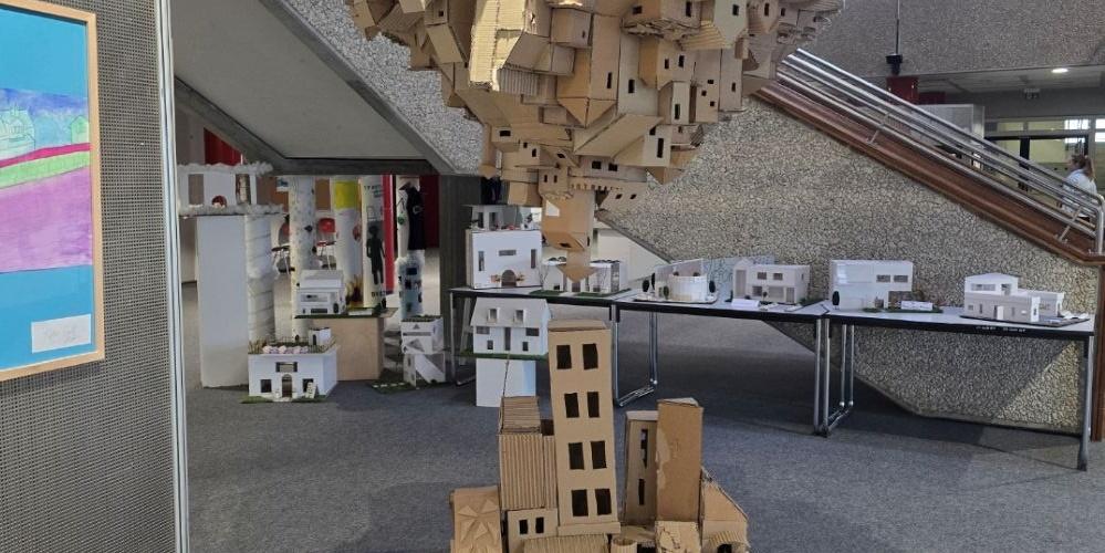 Zwei Städte aus Karton wachsen von Boden und Himmel einander entgegen.