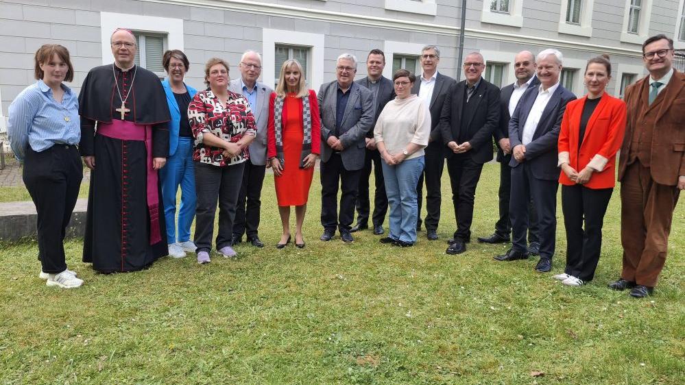 Verantwortliche der Schulstiftung stehen im Garten vor dem Dommuseum.