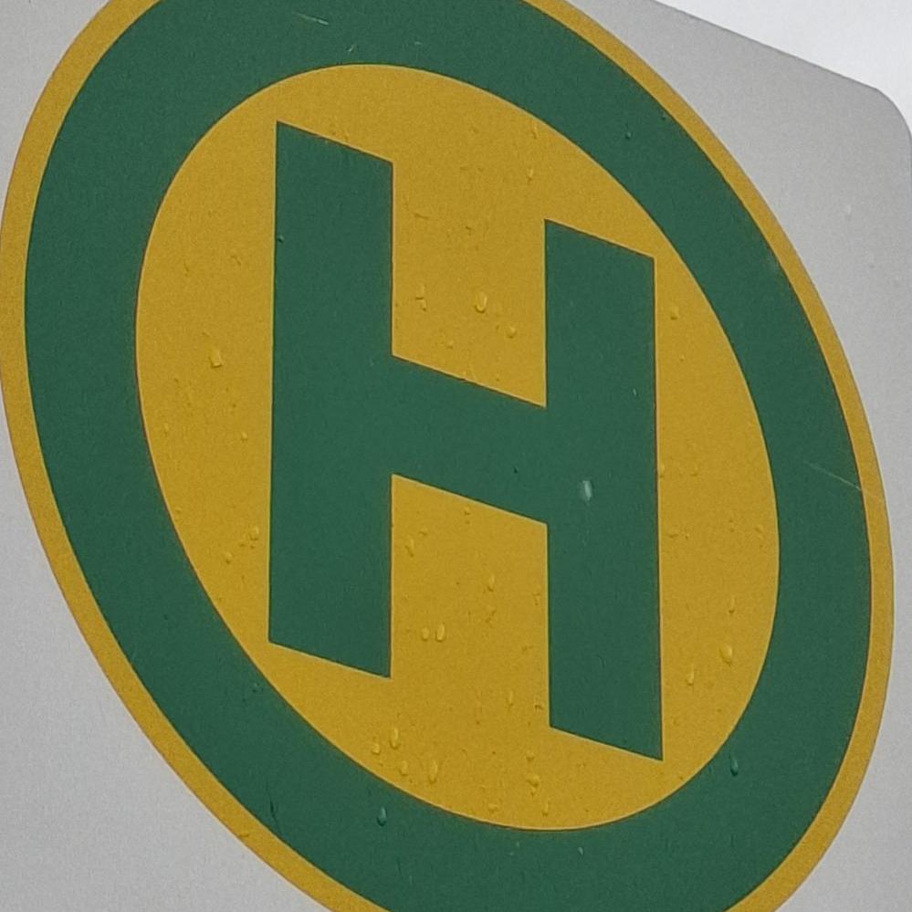 Bushaltestellensymbol: grüner Buchstabe H in grünem Kreis auf gelben Grund